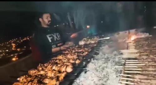 a man is cooking chickens on a grill at Petra Desert Dream Hotel in Wadi Musa
