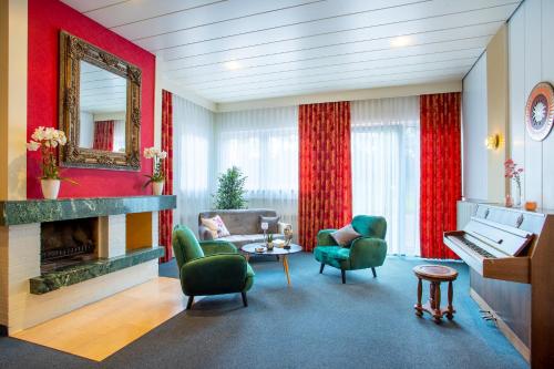a living room with a fireplace and green chairs at Aqualux Wellness- & Tagungshotel in Bad Salzschlirf