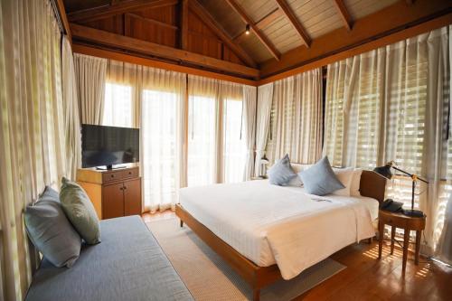 a bedroom with a bed and a tv and windows at Chann Bangkok Noi in Bangkok