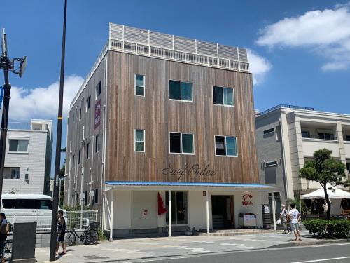 a building on a city street with people standing in front of it at B&B Surf Rider-ゲストハウスタイプ in Kamakura