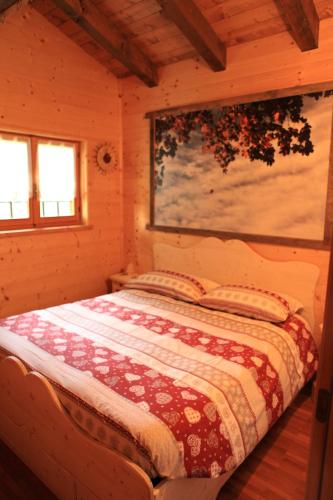 um quarto com uma cama num chalé de madeira em Baita Tana da l'Ors em Forgaria nel Friuli