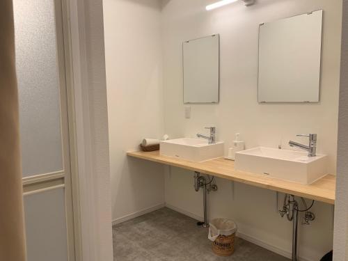 a bathroom with two sinks and two mirrors at B&B Surf Rider-ゲストハウスタイプ in Kamakura