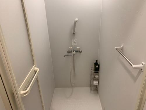 a shower in a white bathroom with a shower at B&B Surf Rider-ゲストハウスタイプ in Kamakura