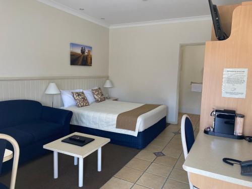 Habitación de hotel con cama y sofá azul en Dalby Mid Town Motor Inn en Dalby