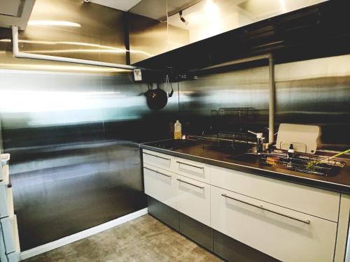 a kitchen with white cabinets and a black wall at B&B Surf Rider-ゲストハウスタイプ in Kamakura