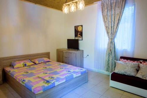 a bedroom with a bed and a tv and a window at Бунгала Камена - Bungalows Kamena in Kamena