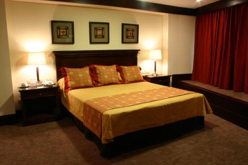 a bedroom with a bed with two lamps and red curtains at Amérian Hotel Casino Gala in Resistencia