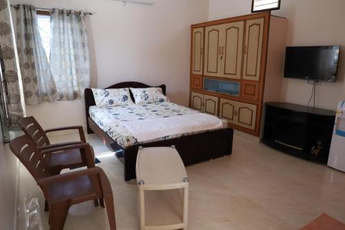 um quarto com uma cama e uma cadeira e uma televisão em DIVINEHOMESTAY COMFORT SUITE em Tirupati