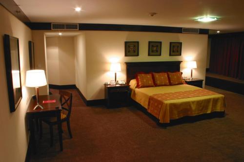 a hotel room with a bed and two tables and two lamps at Amérian Hotel Casino Gala in Resistencia
