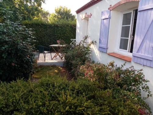 a small white house with a table and a window at l'Eden naturiste écureuil in Challans