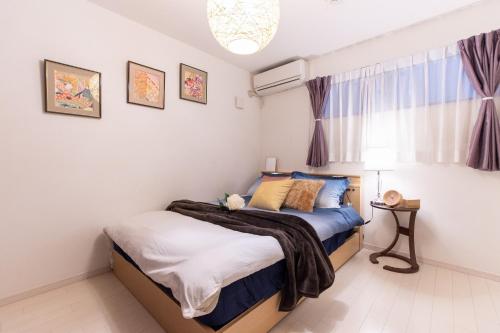 东京CuteFamilyHouse! 6minShinjuku 6minSta FreeParking Cozy,Bright KidsFree Under6yrs的卧室里有一张铺着蓝白床单的床