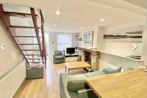 a living room with a staircase and a table and chairs at Traditional 2-bedroom Cornish cottage in Newlyn in Newlyn