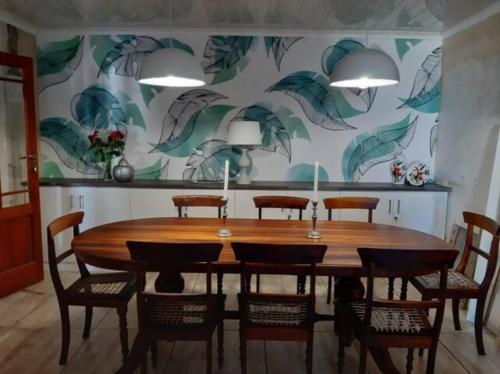 a dining room with a wooden table and chairs at Olive Tree Cottage in Paternoster