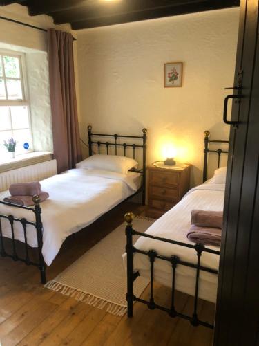 1 dormitorio con 2 camas individuales y ventana en Clannad Cottage, en Arboe