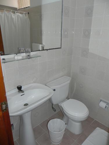 a white bathroom with a toilet and a sink at Hotel Melodia in Lima