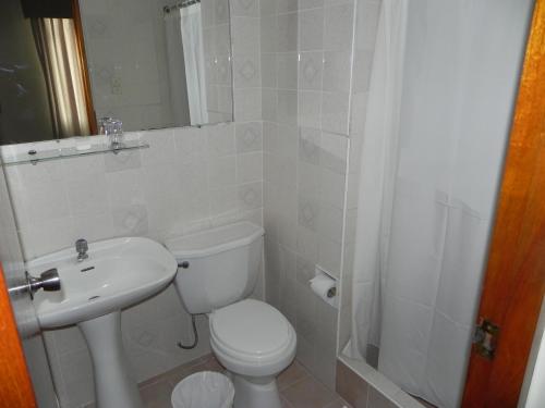 a bathroom with a toilet and a sink and a shower at Hotel Melodia in Lima