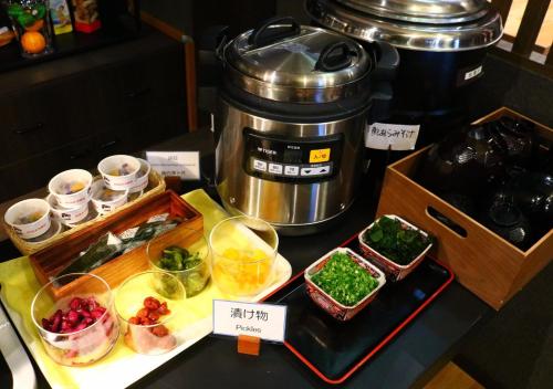 a counter top with a coffee maker and bowls of food at APA Hotel Matsuyamajo Nishi in Matsuyama