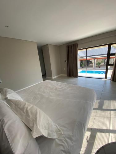 a bedroom with a large white bed and a pool at Khaya Elihle Guest House in Hazyview