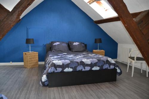 une chambre avec un lit avec un mur bleu dans l'établissement Clos Caritan, à Perdreauville
