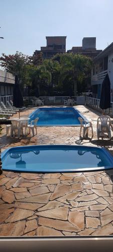 a swimming pool with two chairs and a table at Hotel Pousada Ilha do Mar Bombinhas in Bombinhas