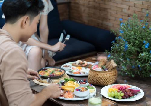 a man sitting at a table with plates of food at Athita The Hidden Court Chiang Saen Boutique Hotel in Chiang Rai