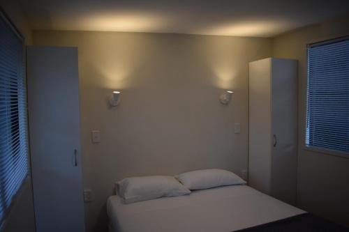 a bedroom with a bed with two pillows on it at Matauri Bay Holiday Park in Matauri Bay