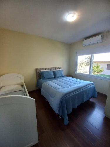 a bedroom with a blue bed and a window at Casa Ari Candiago Gramado in Gramado
