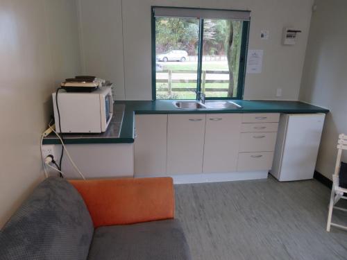 a kitchen with a counter with a sink and a microwave at Matauri Bay Holiday Park in Matauri Bay