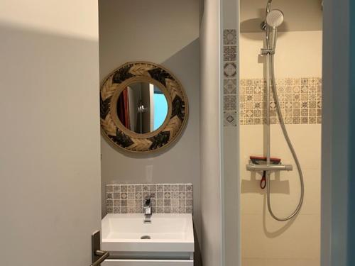 een badkamer met een wastafel en een spiegel bij L'Appartement vue mer de la Villa des Rosiers - Trouville sur Mer in Trouville-sur-Mer