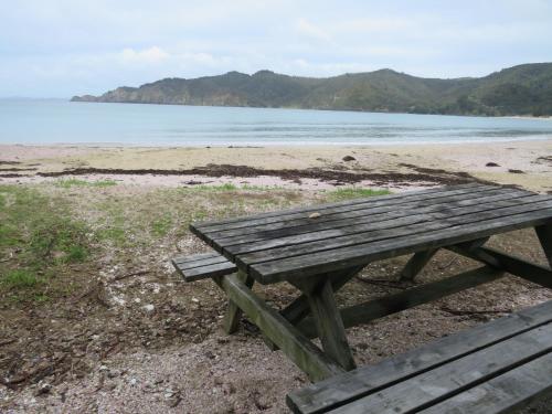 a wooden picnic table sitting on the beach at Matauri Bay Holiday Park in Matauri Bay