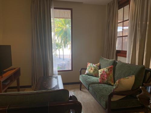a living room with a green couch and a window at Viluveli Holiday Retreat in Hanimaadhoo