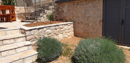 a garden with a stone wall and some bushes at Apartmani STJEPAN in Zavala