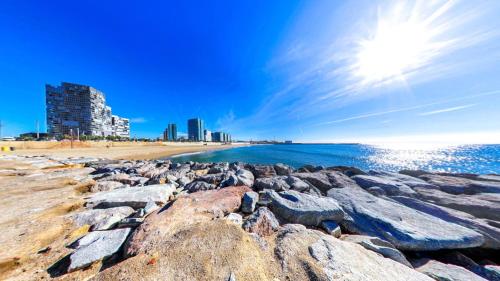 a beach with rocks and buildings in the background at Hotel BESTPRICE Diagonal in Barcelona