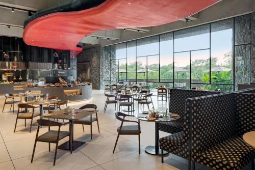 a restaurant with tables and chairs and windows at Radisson Resort and Spa Lonavala in Lonavala