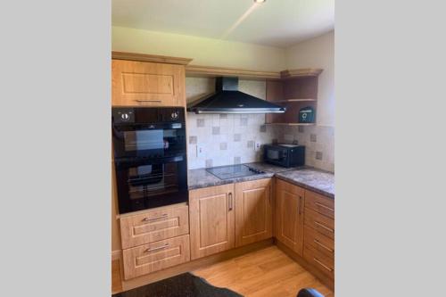 a kitchen with wooden cabinets and black appliances at Quintenvale House in Kilkeel