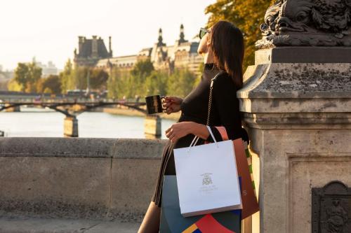 a woman holding a cup and a shopping bag at Hôtel D'Aubusson in Paris