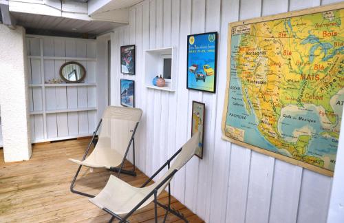 ein weißer Stuhl und eine Karte an einer Wand in der Unterkunft les coquilles in Lanton