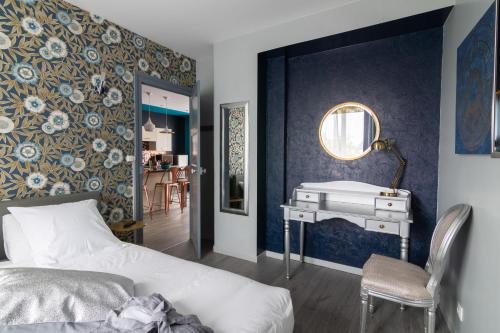1 dormitorio con cama, escritorio y espejo en Oasis Anjou, en Saumur