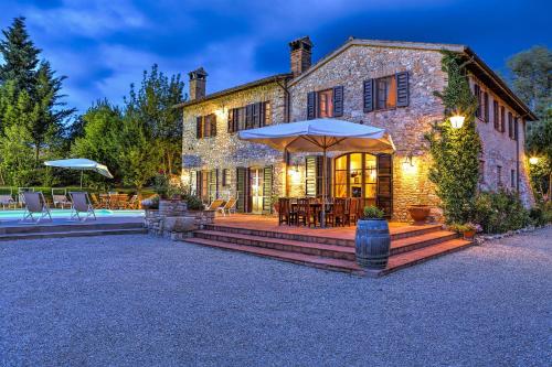 a stone house with a patio with an umbrella at L’Aurora in Todi