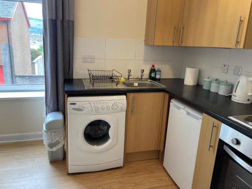 a kitchen with a washing machine and a sink at Rainforest 1 in Campbeltown