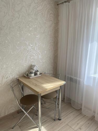 a table and chairs in a room with a wall at Уютные апартаменты на Речном in Tver