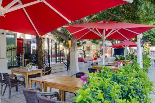 a patio with tables and chairs with red umbrellas at The Hello Hotel in Gümbet