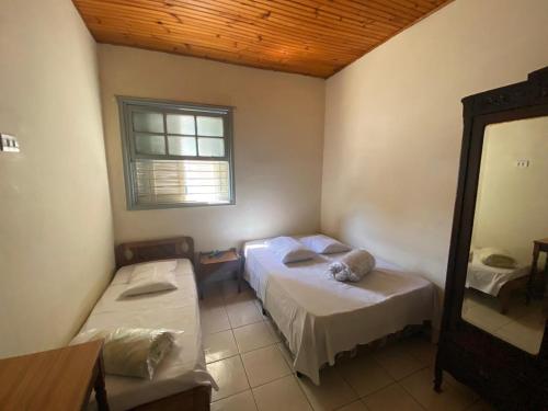 a room with two beds and a mirror in it at Hotel São Paulo in Poços de Caldas