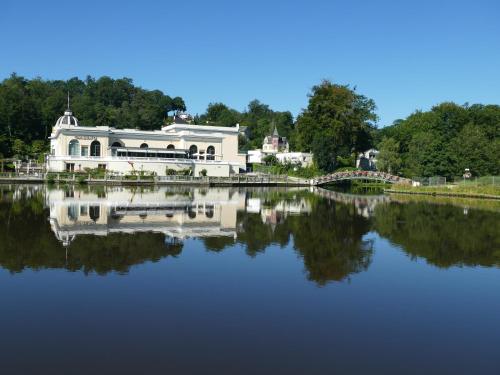 un edificio blanco sobre el agua con un puente en appartement au Hameau du parc des thermes, en Bagnoles de l'Orne