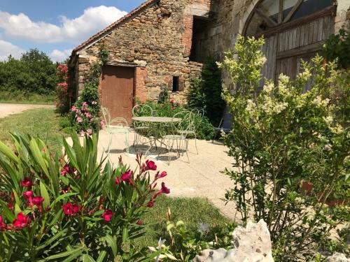 - un jardin avec une table et des chaises en face d'un bâtiment dans l'établissement La Barcelle, une pause nature., à Perrigny