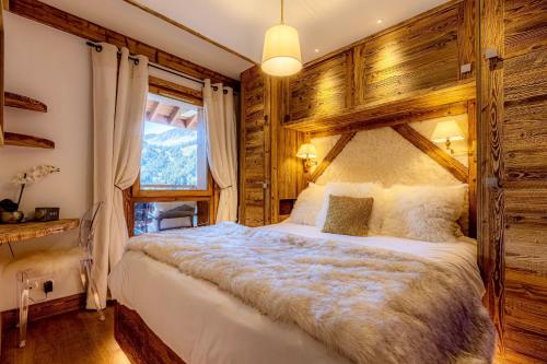 een slaapkamer met een groot bed en een houten muur bij Arc 1950, ambiance chalet luxe 5/7pers dans résidence 5* skis aux pieds avec SPA in Arc 1950