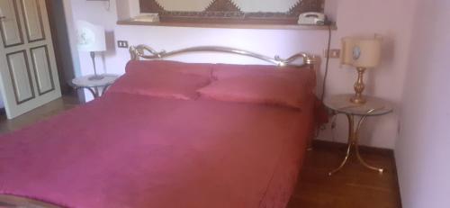Appignano的住宿－Appartamento in villa，一张红色的床,位于带两张桌子的房间