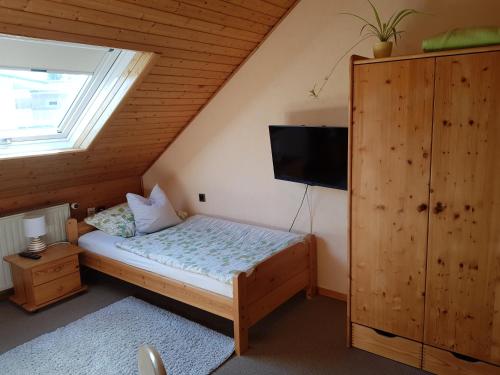 Dormitorio pequeño con cama y TV en Gästezimmer Aschenbrenner en Bad Rodach