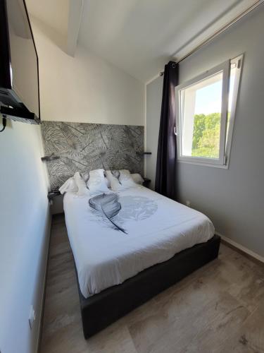 a bedroom with a large white bed with a window at Les Prairies de l'Encrême in Céreste