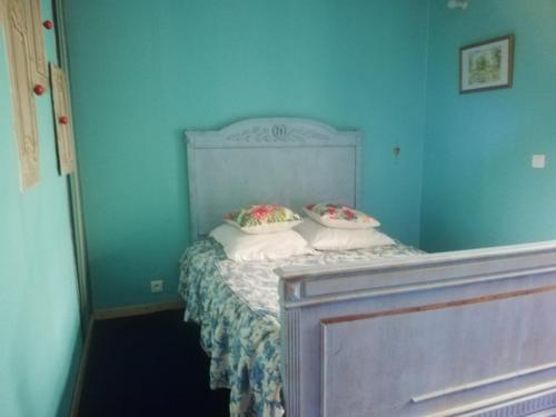 a blue bedroom with a bed with two pillows at Hôtellerie Jardiniers Gourmands in Morsains